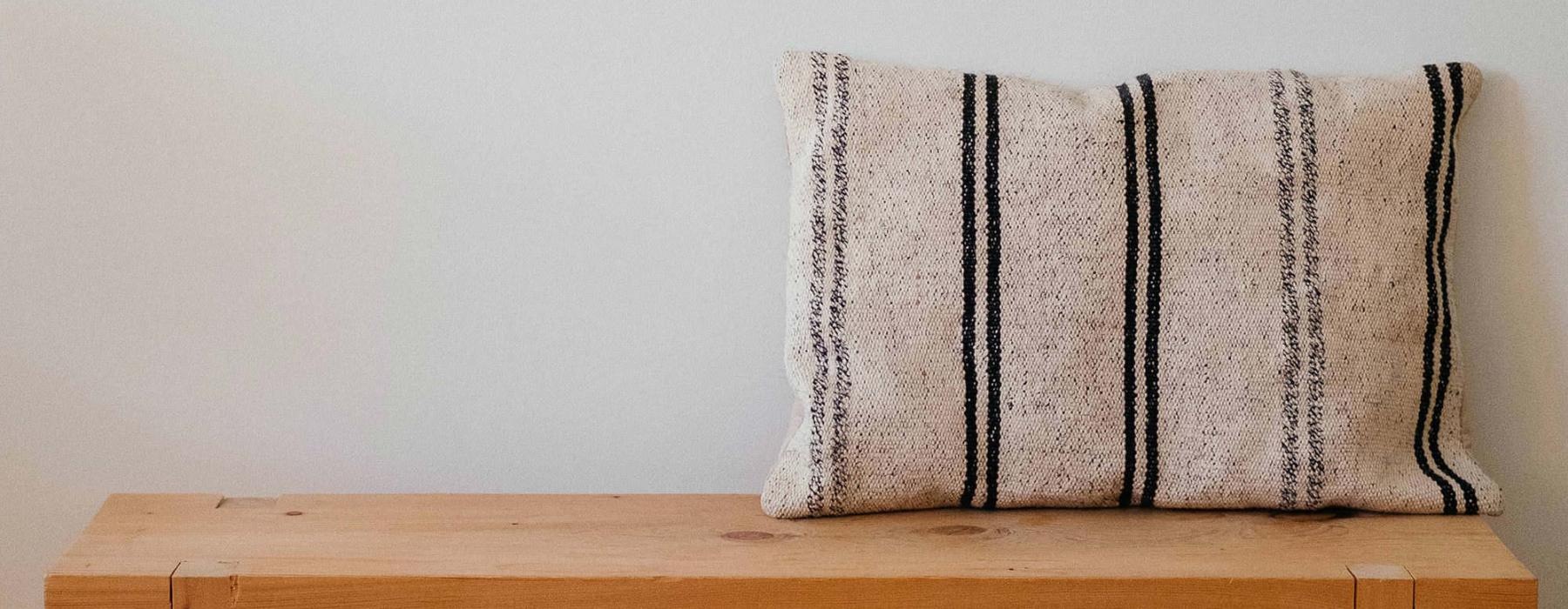 a wooden bench with a striped pillow on it